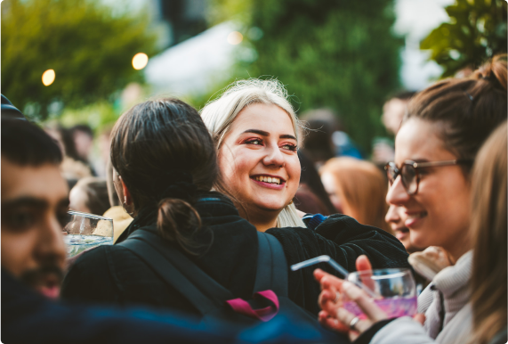 A group of students talking and smiling in a large crowd