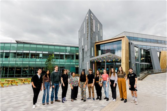 A female student waving to the camera whilst stood in a large crowd